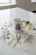 Taza escarabajo flat lay místico con flores secas y cristales sobre mármol blanco