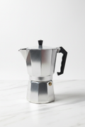 Cafetera italiana Moka plateada sobre mármol blanco fondo limpio profesional
